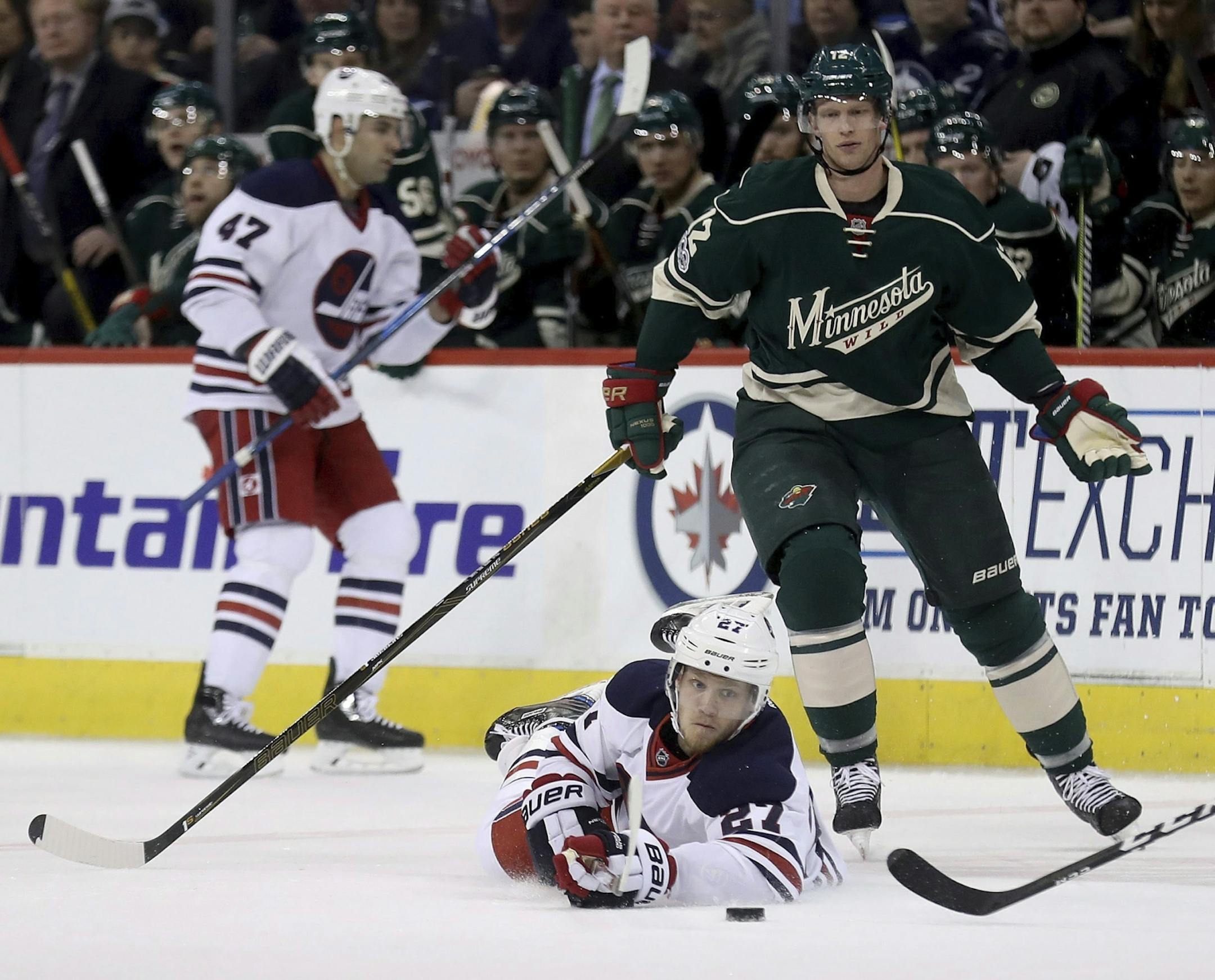 Winnipeg Jets' Nikolaj Ehlers (27) is tripped by Minnesota Wild's Eric Staal (12) during the second period of an NHL hockey game in Winnipeg, Manitoba, Sunday, March 19, 2017.