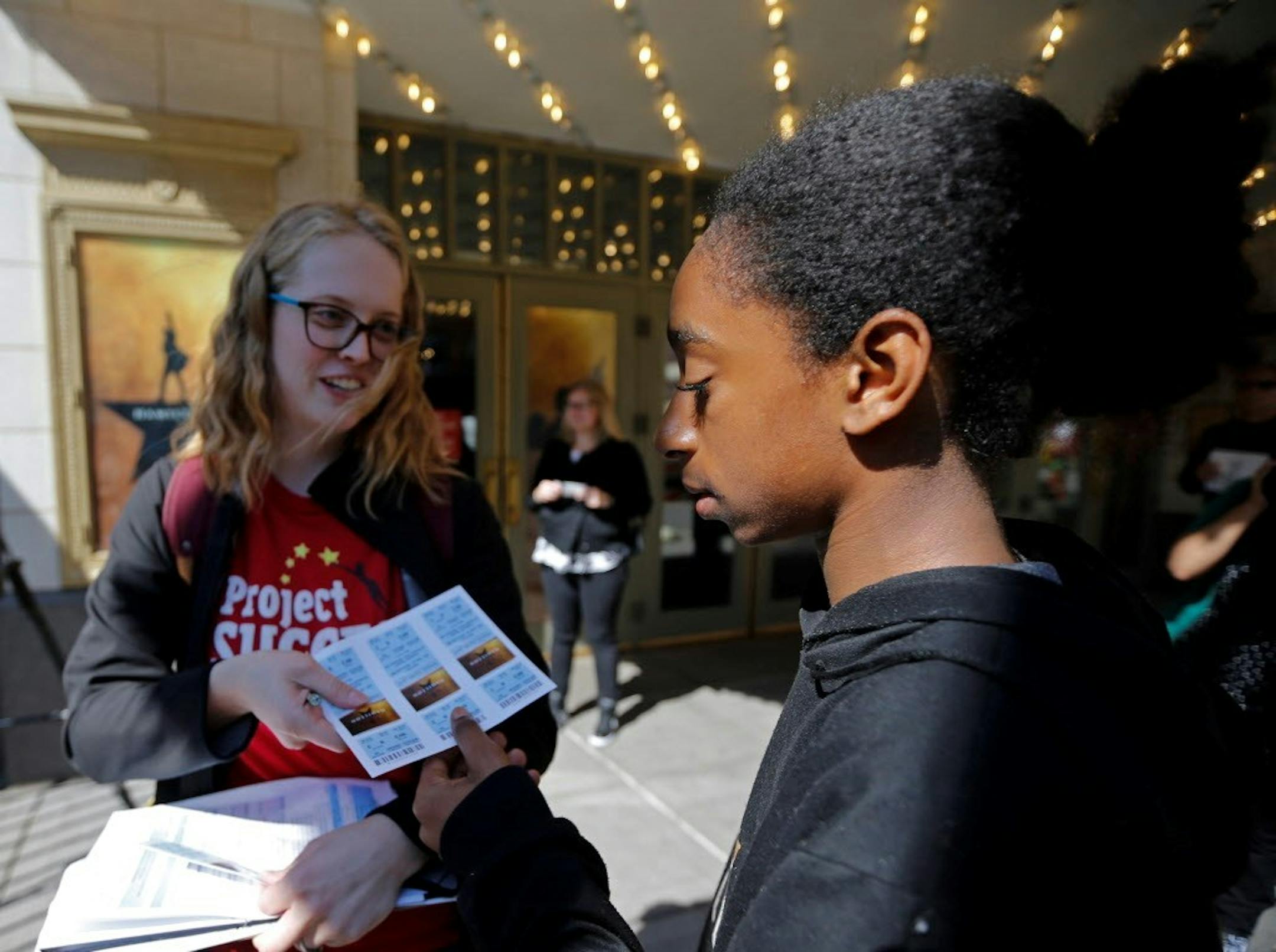 Kahlil Burge, an eighth grader at Folwell School, accepted tickets from Project Success employee Kiah Eide to see the matinee performance of Hamilton at the Orpheum Theater.