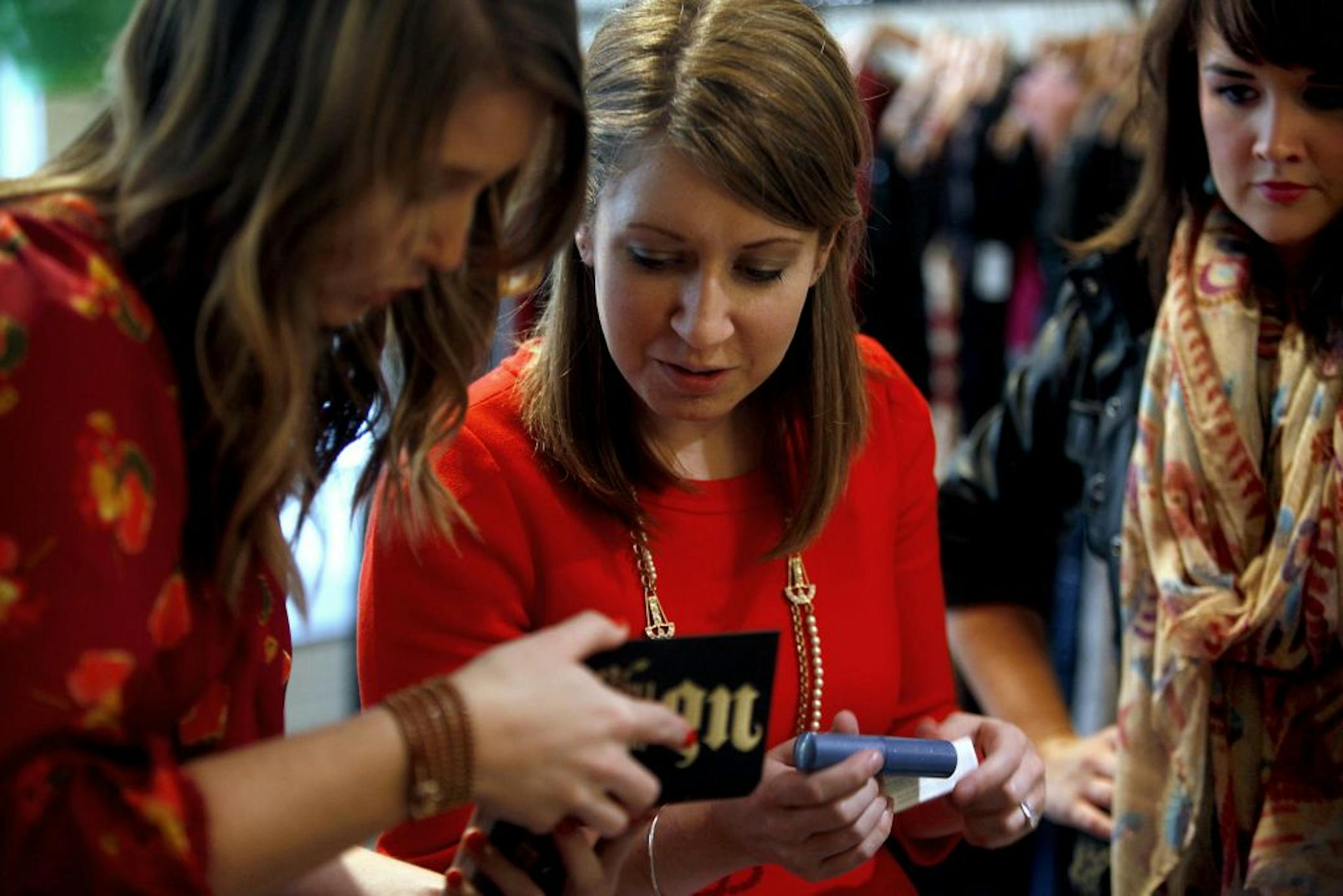 Katie Stedman, Katie Najjar and Danielle Bruflodt browse through the items that were brought in by other attendees of a beauty product exchange.