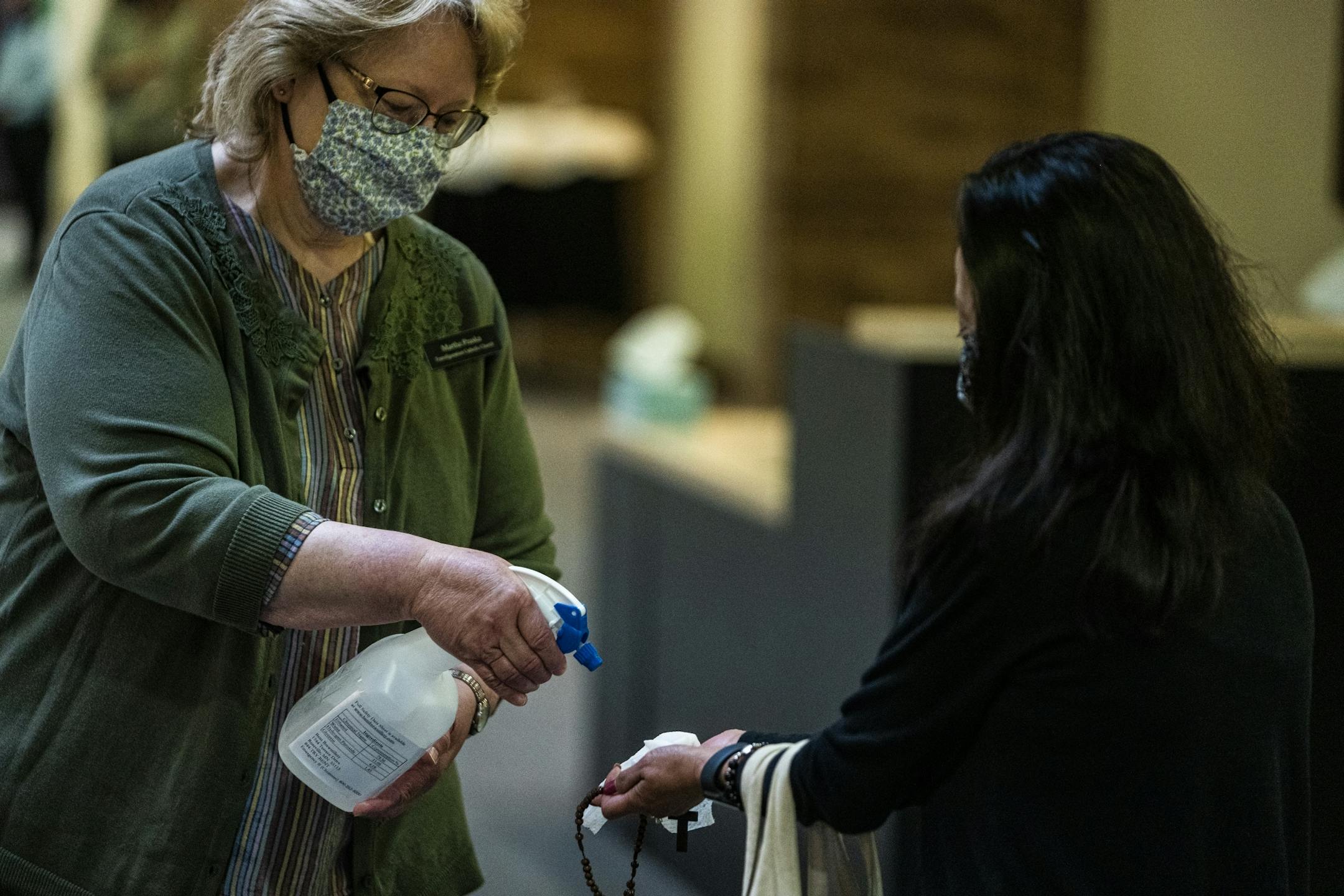 Church administrator Martha Praska sanitized parishioner Del Sliter's hands as she entered the church.