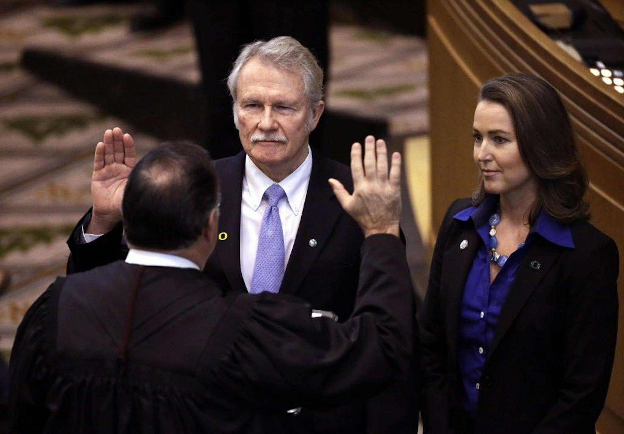 FILE - In this Jan. 12, 2015 file photo, Oregon Gov. John Kitzhaber, middle, is joined by his fiancee, Cylvia Hayes, as he is sworn in for an unprecedented fourth term by Senior Judge Paul J. De Muniz in Salem, Ore.