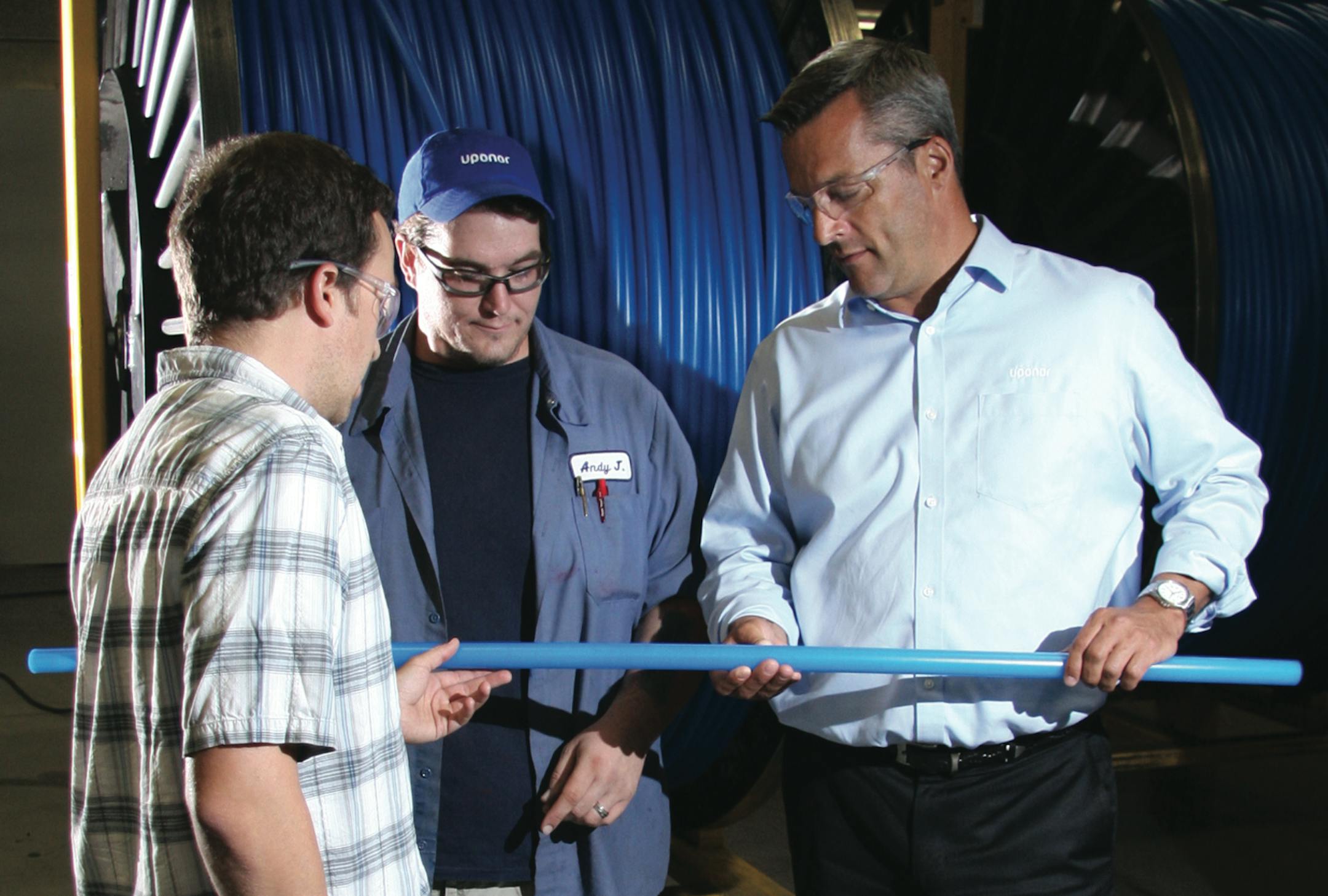 Uponor North America's Bryan Baxter (left), a process engineer; Andy Jensen, barrier line operator; and President Bill Gray inspect tubing manufactured in Apple Valley.