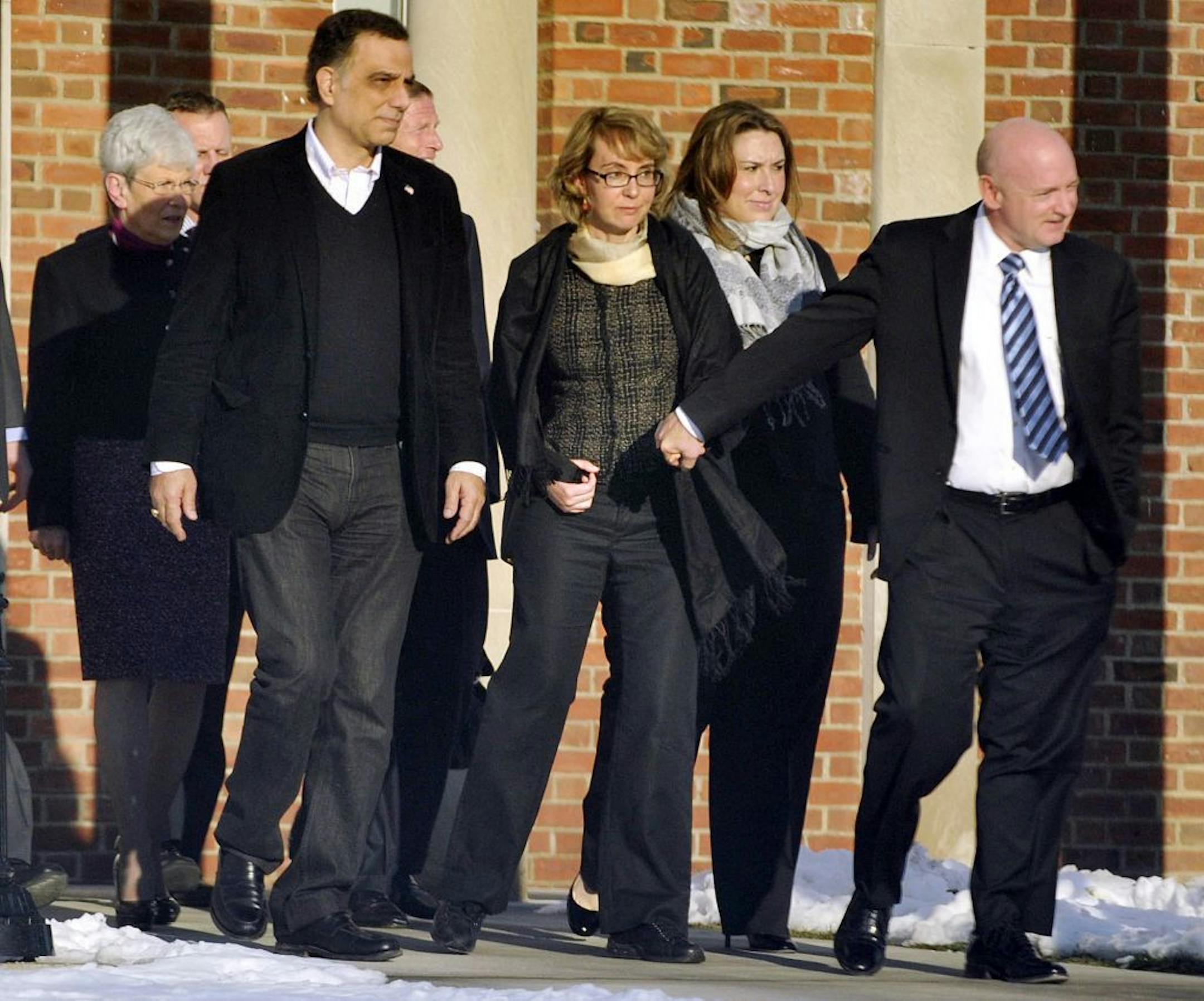 Former U.S. Rep. Gabrielle Giffords, center, holds hands with her husband, Mark Kelly, while exiting Town Hall at Fairfield Hills Campus in Newtown, Conn. after meeting with Newtown officials in this Jan. 4, 2013 photo.