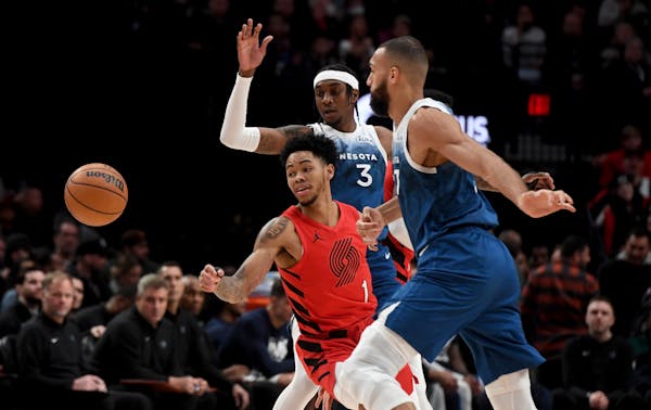 Trail Blazers guard Anfernee Simons passed between Wolves forward Jaden McDaniels, rear, and center Rudy Gobert in a Feb. 13 game in Portland. The Wol