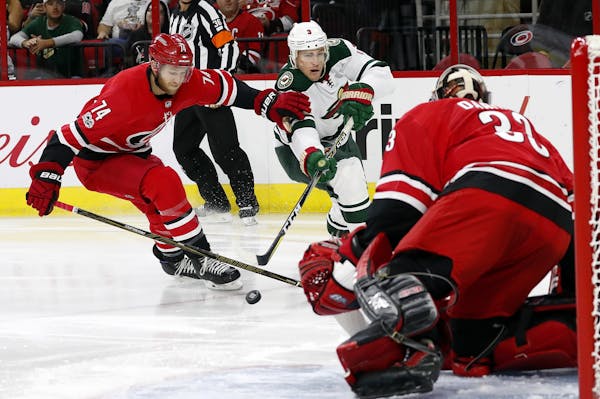 Minnesota Wild's Charlie Coyle (3) breaks away from Carolina Hurricanes' Jaccob Slavin (74) to shoot the puck at goalie Scott Darling (33) during the 