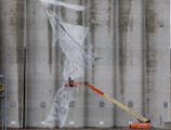 Australian artist Guido van Helten braved cold, wet weather and 40 mph wind gusts to start work on a massive mural on the Ardent Mills grain silos in 