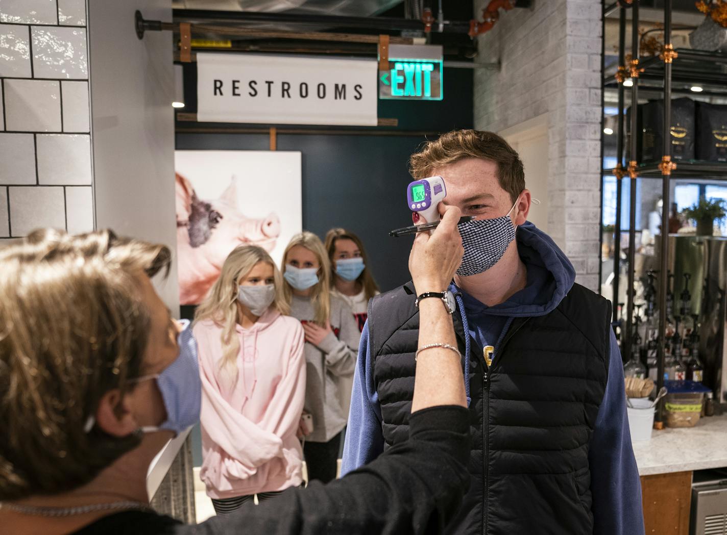 Grocer's Table employee Drew Sigel had his temperature checked before clocking in on Tuesday, part of a new health screening for employees. When the restaurant reopens Wednesday, indoor seating will be down to less than 25% capacity.