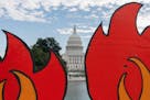 In this Oct. 15, 2021, the U.S. Capitol is seen between cardboard cutouts of flames during a climate change protest near the U.S. Capitol in Washingto