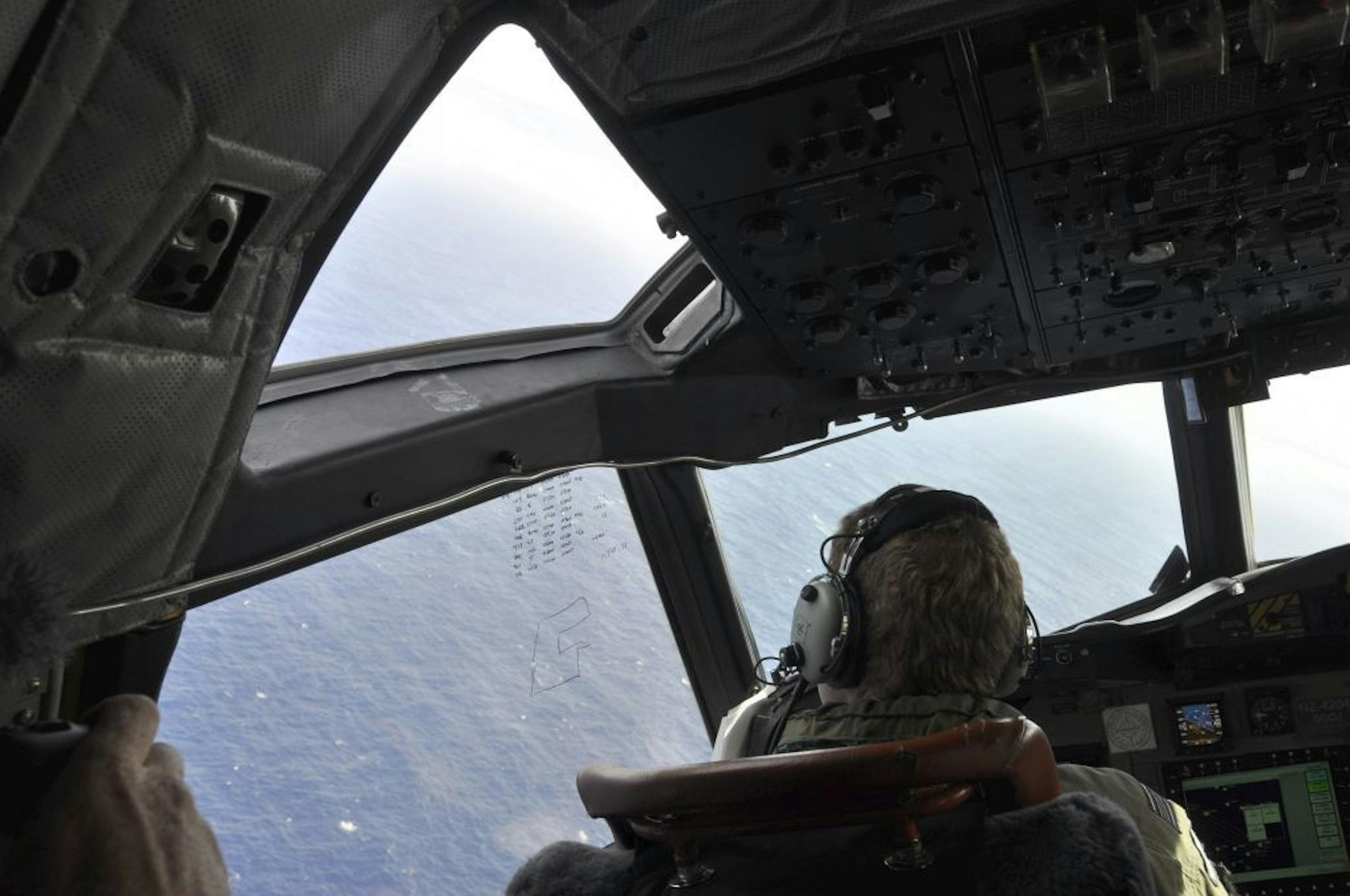In this Tuesday, April 1, 2014 photo, a crewman on a Royal New Zealand Air Force P-3 Orion Rescue Flight 795 searches for debris from the missing Malaysia Airlines Flight MH370, in southern Indian Ocean.