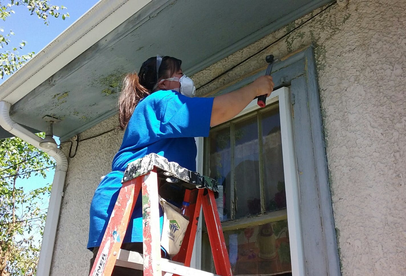 Submitted photo from Hennepin County. Ashley Hillyer, a grant accountant with Hennepin County Human Services and Public Health, chipped and scraped windows on July 9 at a north Minneapolis home. Hillyer was one of 12 members of the county&#xed;s Asian Connections Employee Resource Group working on a Habitat for Humanity project.