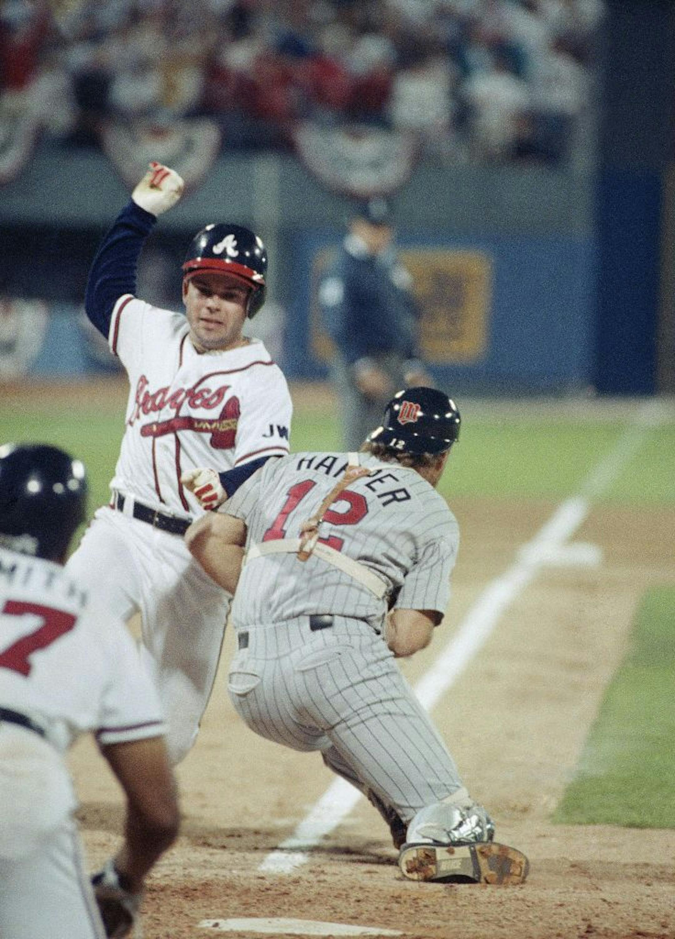 Atlanta Braves Mark Lemke (20) scores past Minnesota Twins catcher Brian Harper (12) to win game four of the World Series in the ninth inning on a Jerry Willard sacrifice fly, Wednesday, Oct. 23, 1991, Atlanta, Ga. The win tied the series at 2 games each.