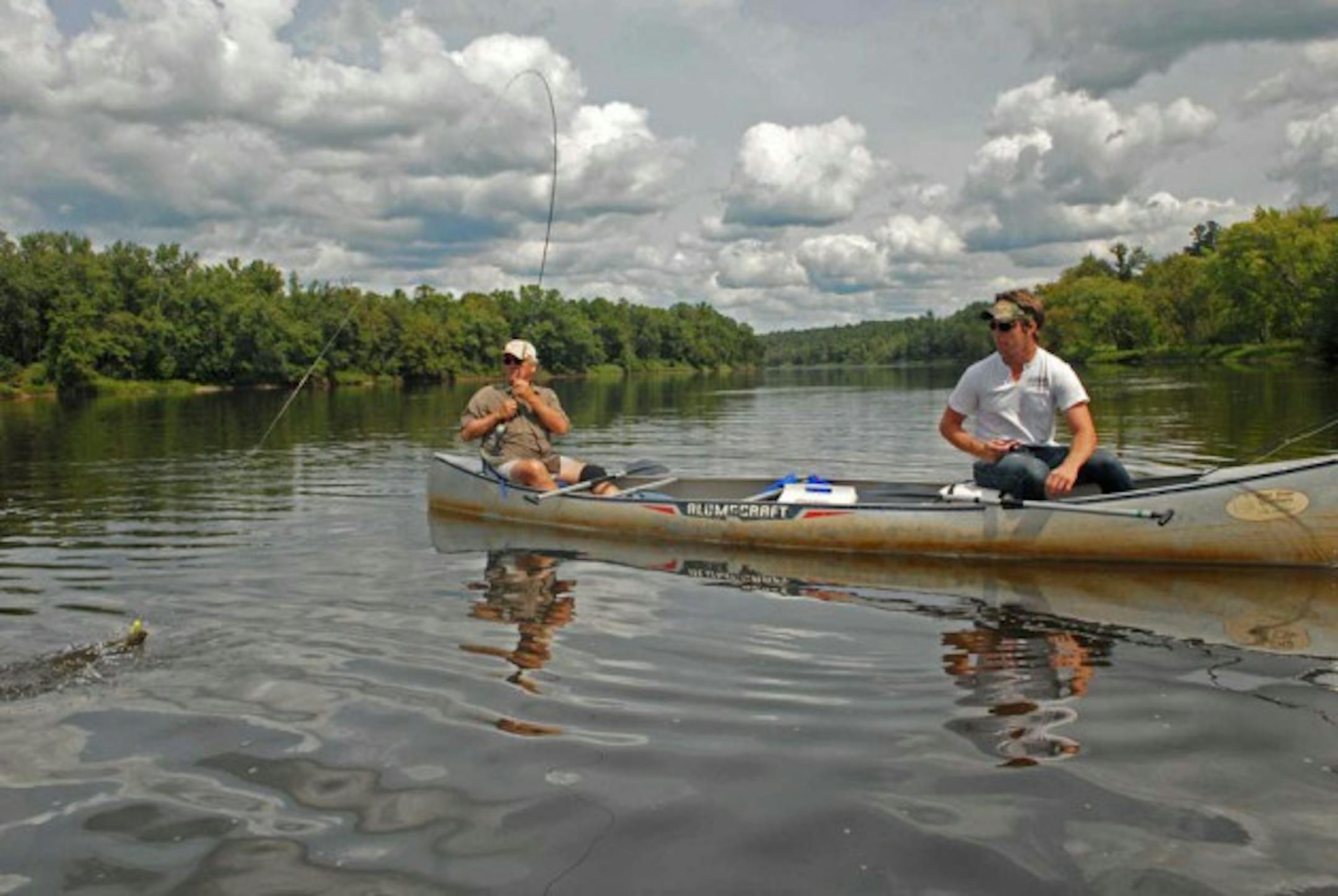 Bob Nasby, left, and his grandson, Bobby McGraw, take in the sights of the Upper St. Croix River while Nasby lands a smallmouth bass on his fly rod.