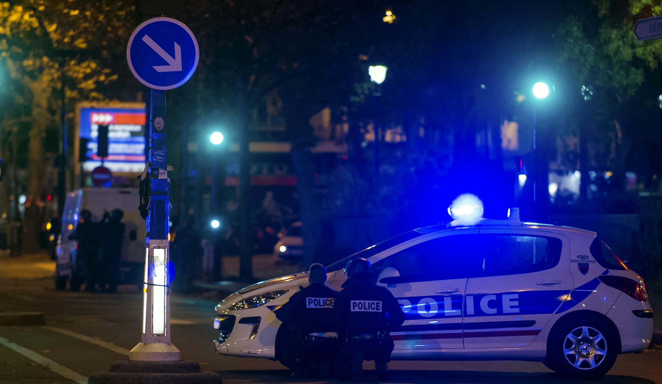 A police officer takes cover behind cars outside the Bataclan theater in Paris, France, Wednesday, Nov. 13, 2015. Several dozen people were killed in a series of unprecedented attacks around Paris on Friday, French President Francois Hollande said, announcing that he was closing the country's borders and declaring a state of emergency. (AP Photo/Kamil Zihnioglu) ORG XMIT: MIN2015111318420883