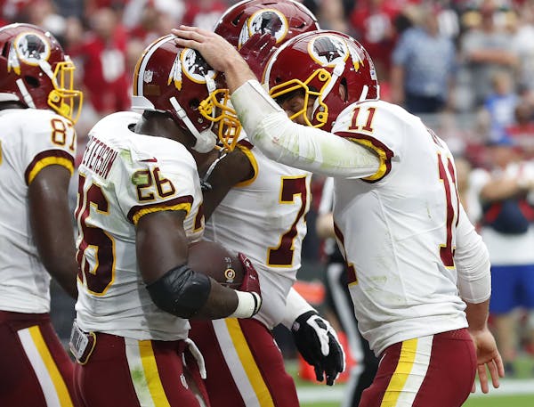 Washington Redskins running back Adrian Peterson (26) celebrates his touchdown run with quarterback Alex Smith (11) during the first half of an NFL fo