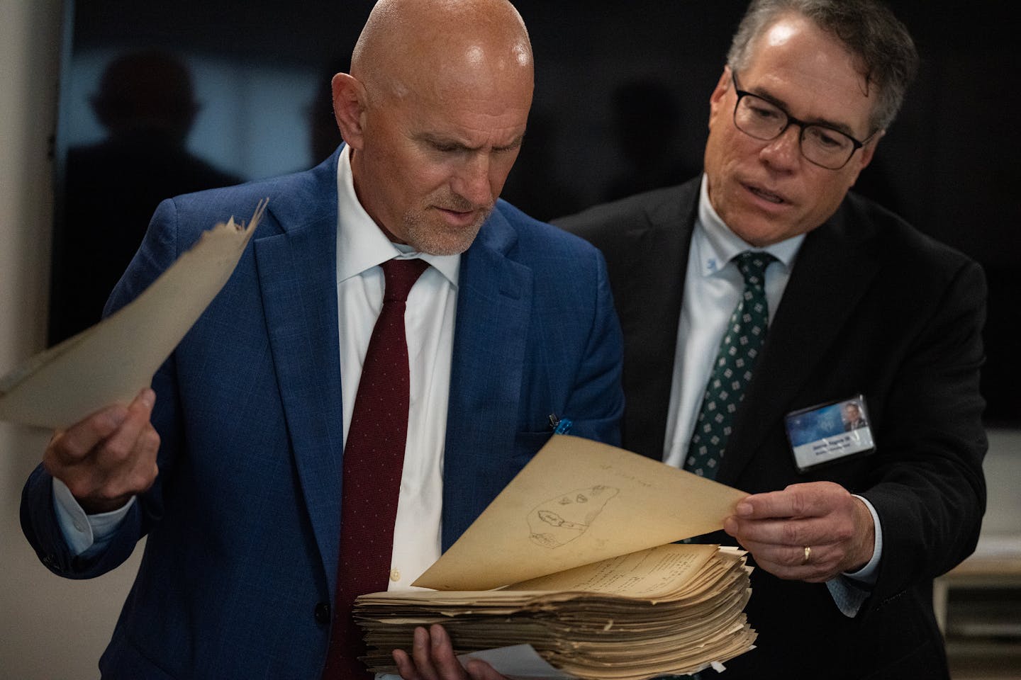 Dr. Matthew Callstrom, left, Mayo Clinic’s generative AI program head, and Digital Pathology CEO Jim Rogers check out a patient file from the early 1900s.