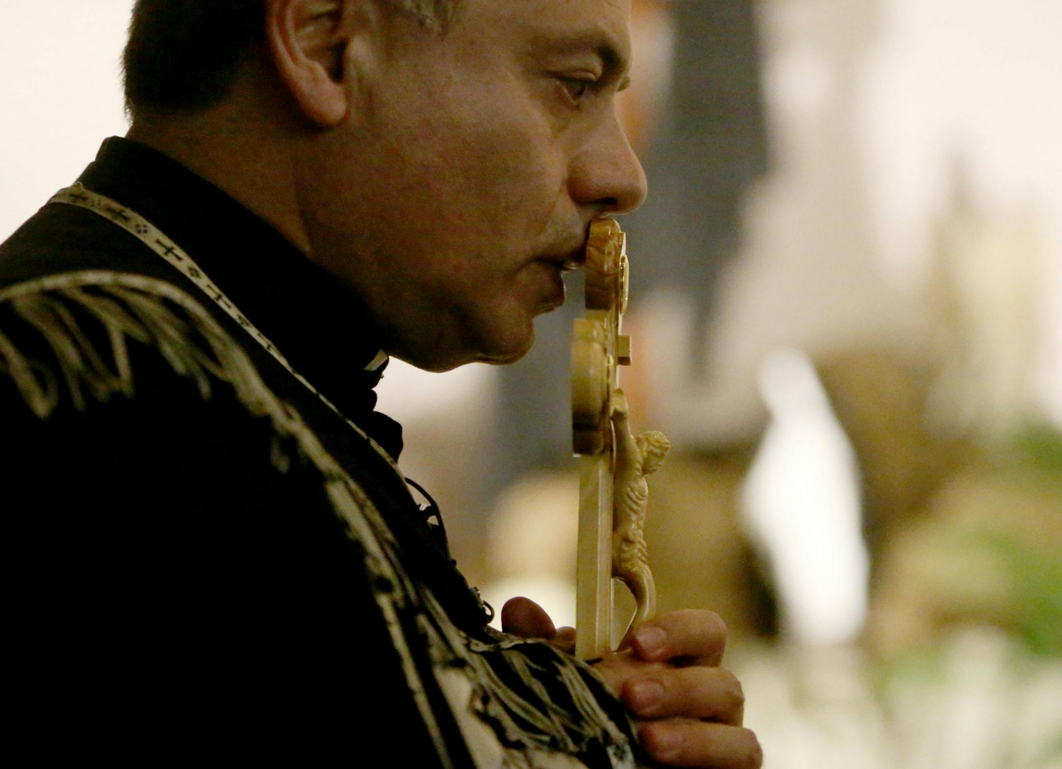 Pastor Sharbel-Ghattas Maroun kisses the crucifix at the conclusion of a Good Friday service Friday, March 26, 2016, at St. Maron's Catholic Church in Minneapolis.