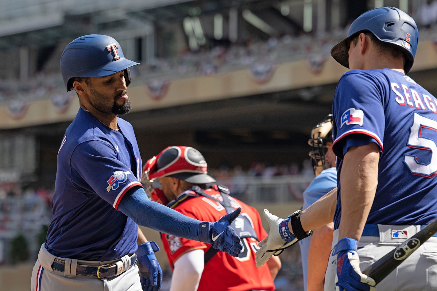 Marcus Semien, left, high-fives Rangers teammate Corey Seager, right, after hitting a home run during the fourth inning against the Twins on Sunday