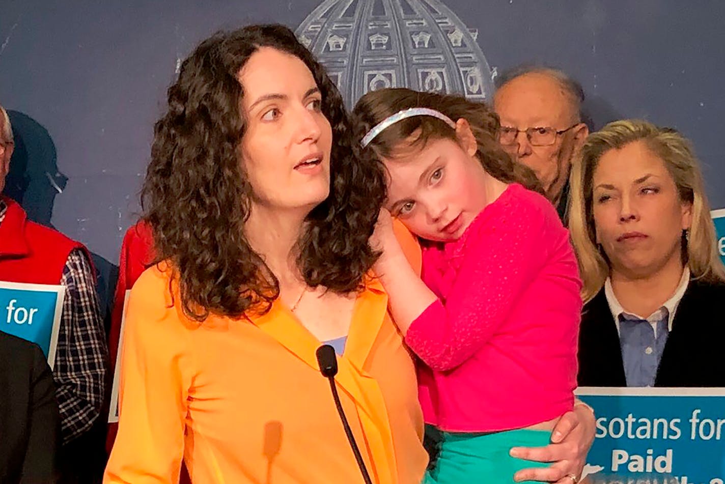 Dr. Hannah Lichtsinn of Minnesota Doctors for Health Equity holding her 6-year-old daughter, Linnea, speaks at a news conference at the state Capitol in St. Paul, Minn., on Thursday. March 5, 2020, in support of a bill that would guarantee Minnesota workers the right to paid family and medical leave.