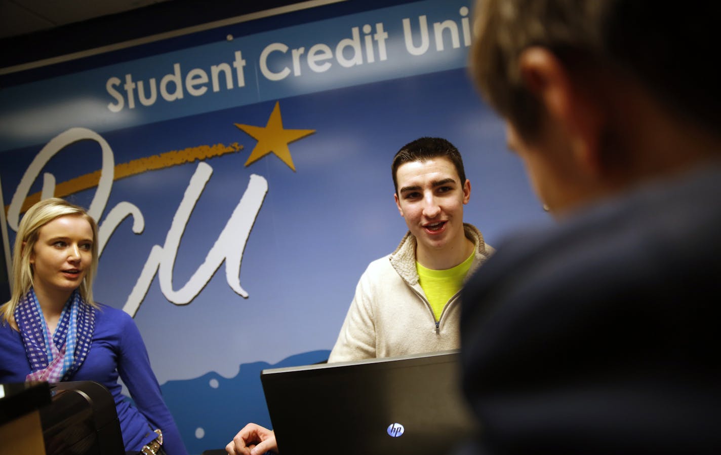 At Postal Credit Union&#x2019;s branch at Tartan High School in Oakdale, students Geneva Eilertson and Marc Buchmayer tried to convince Elijah McGeehan, right, to open an account. The branch has its own automated teller machine, but no credit cards, just debit cards.