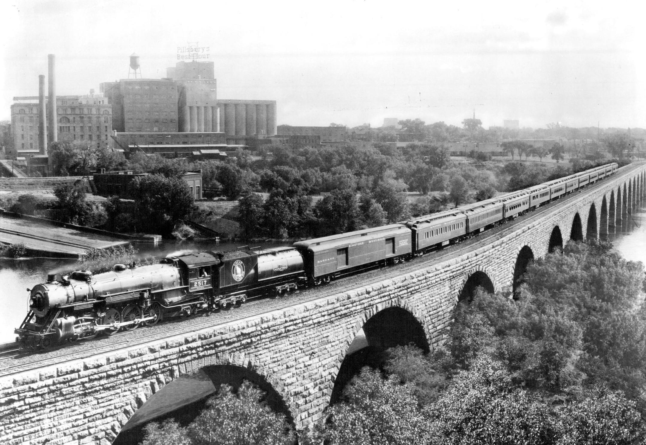 June 3, 1954 Great Northern Railway's first Empire Builder, which entered service in 1929, is shown on the Stone Arch Bridge crossing the Mississippi river in Minneapolis. Locomotive and bridge are historic too. No. 2517 won the "Marathon" appearing on its tender, in 1925 by making a fast 3,600-mile round trip between Seattle and St. Paul without requiring mechanical attention. It powered a special silk train eastbound and Great Northern's Fast Mail westbound.The bridge, completed in 1883, is th