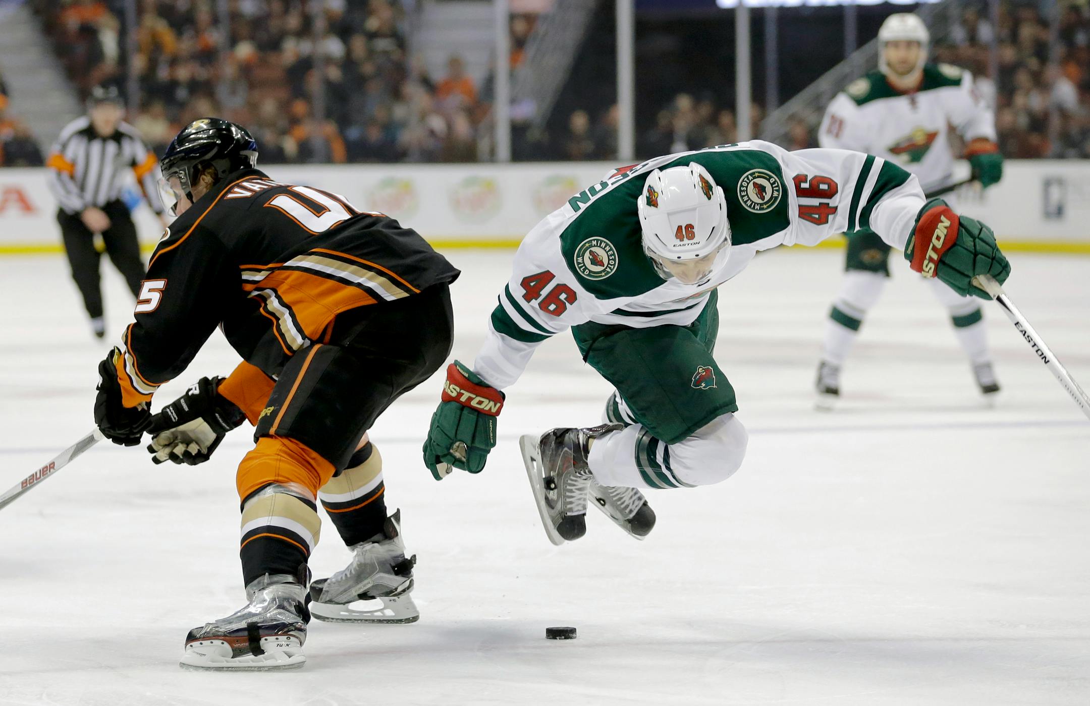 Minnesota Wild defenseman Jared Spurgeon, right, flies over the puck as Anaheim Ducks defenseman Sami Vatanen skates by during the first period of an NHL hockey game in Anaheim, Calif., Wednesday, Jan. 20, 2016. (AP Photo/Chris Carlson)