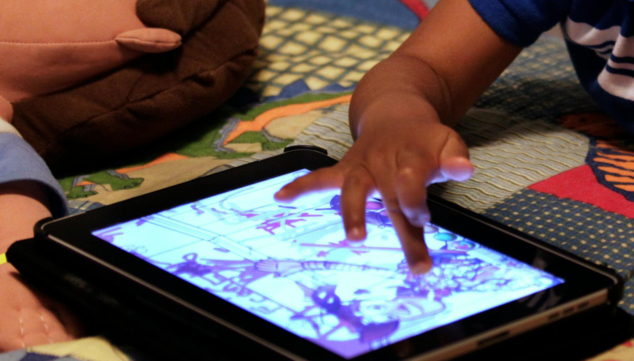FILE - In this Friday, Oct. 21, 2011, file photo, a child plays with an iPad in his bedroom. Parents of small children have long been hearing about the perils of "screen time." And with more screens, it's only getting worse. But working, taking care of children and remembering to eat is exhausting. Parents need those minutes of quiet. So maybe it's time to relax a little. (AP Photo/Gerald Herbert, File) ORG XMIT: NYBZ442