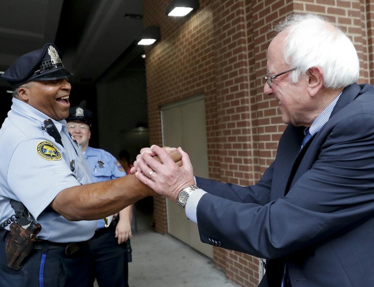 Sen. Bernie Sanders, I-Vt., right, greets a police officer during walk around downtown in Philadelphia, Thursday, July 28, 2016, during the final day of the Democratic National Convention. (AP Photo/John Minchillo)