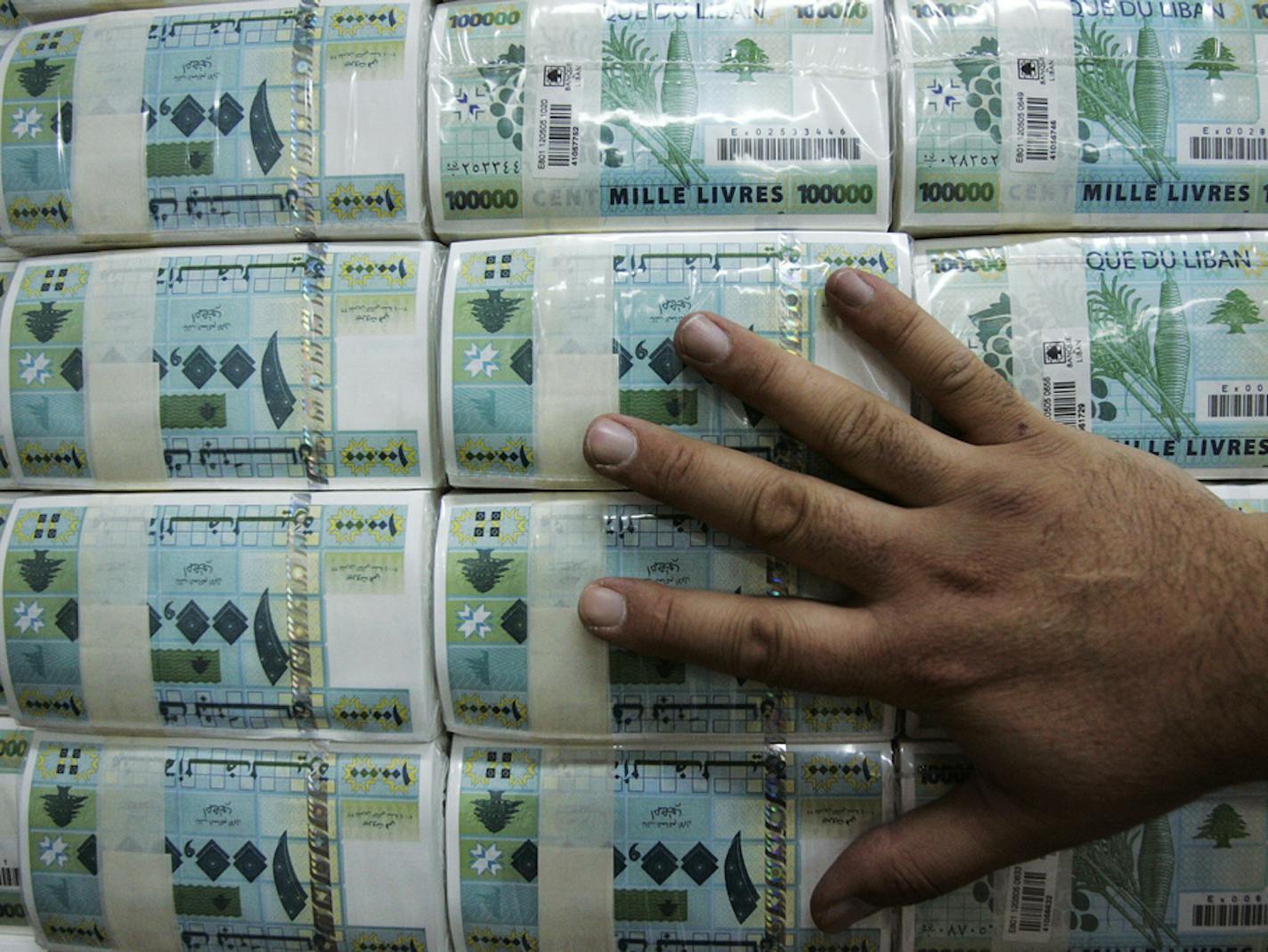 FILE -- This Nov. 26, 2008, file photo, an employee stacks packets of currency in the Central Lebanese Bank in Beirut, Lebanon. Lebanon's central bank has issued guarantees to secure U.S. dollars for local banks at the fixed official rate that would cover imports of fuel, wheat and medicine. The central bank's move on Tuesday, Oct. 1, 2019 aims to ease the demand for dollars at a time when many Lebanese are rushing to exchange shops to convert their local currency into dollars. (AP Photo/Hussein