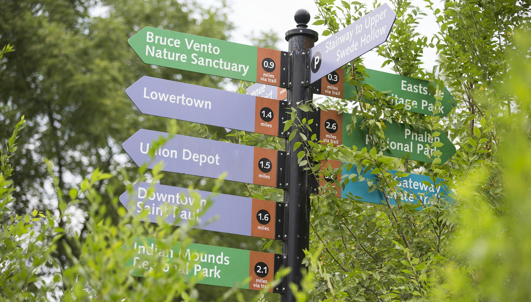 Signs pointing to landmarks in Swede Hollow Park in St. Paul.
