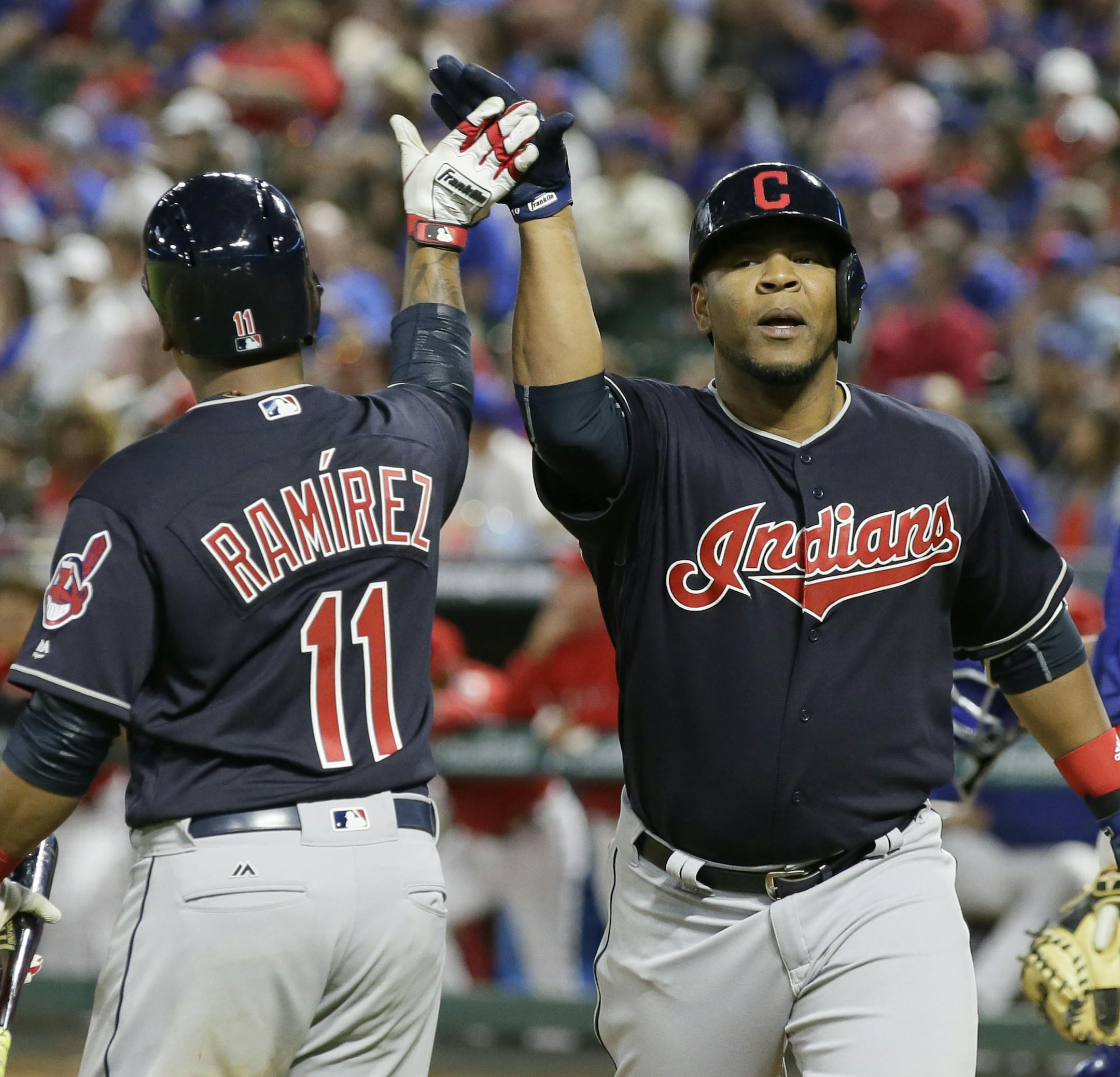 Cleveland Indians Edwin Encarnacion, center, is congratulated after a solo home run during the eighth inning of an opening day baseball game against the Texas Rangers in Arlington, Texas, Monday, April 3, 2017. (AP Photo/LM Otero)