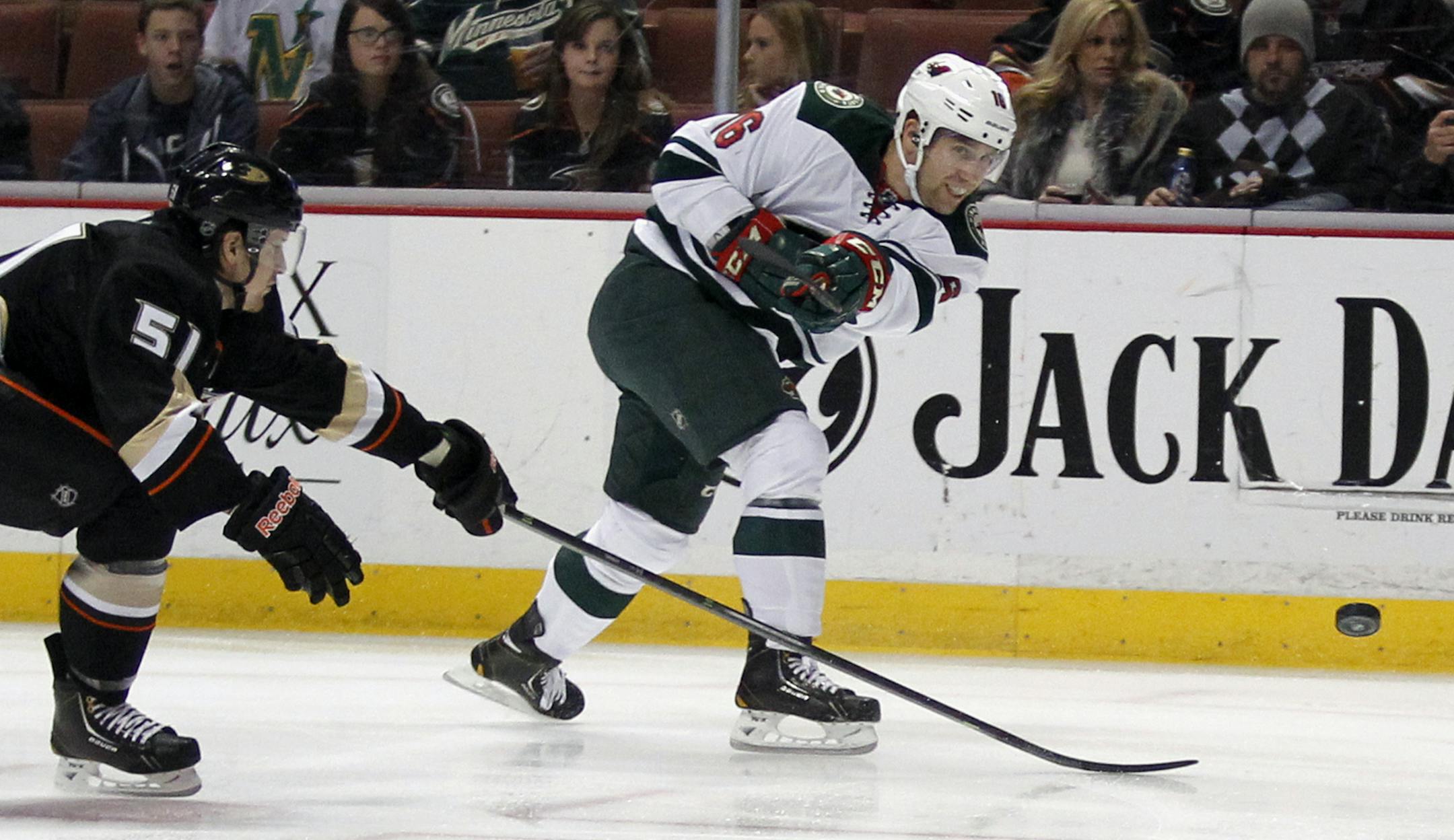 Minnesota Wild left wing Jason Zucker, right, takes a shot on-goal with Anaheim Ducks defenseman Alex Grant (51) defending in the first period of an NHL hockey game on Wednesday, Dec. 11, 2013, in Anaheim, Calif. (AP Photo/Alex Gallardo)