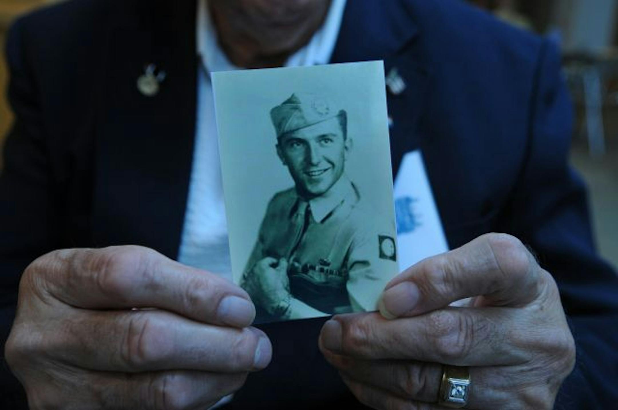 Ed Haider holds a photo of himself as a young solider at Fort Benning GA.