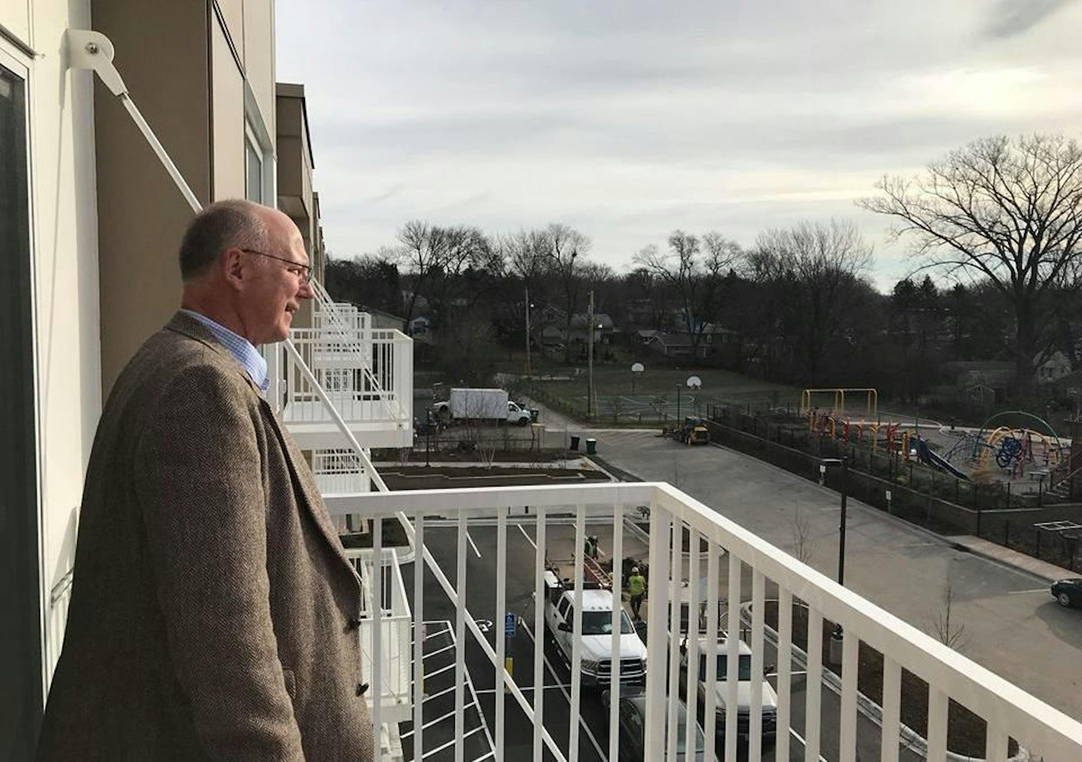 Chris Wilson, the senior director of real estate development at Project for Pride in Living, looks out from the balcony of Oxford Village, a new 51-unit affordable housing complex along Blake Road N. in Hopkins.