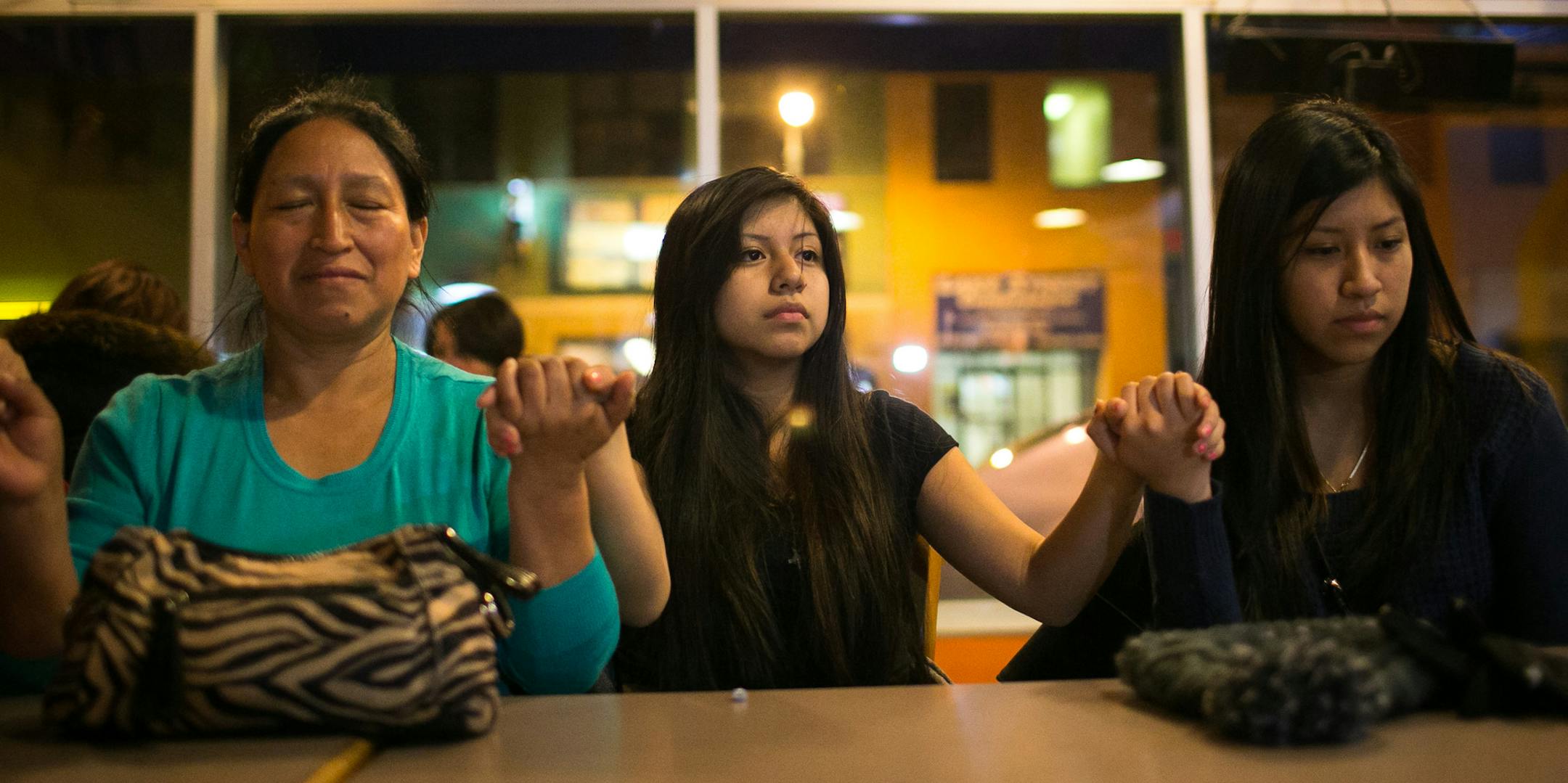 From left, Rosa Sari, Erika Tacuri and Rose Tacuri take part in a prayer lead by Reverend Howard Dotson after President Obama's speech on immigration reform Thursday, Nov. 20, 2014 at Mercado Central. ] AARON LAVINSKY • aaron.lavinsky@startribune.com Activists watch as President Obama announces an executive order on immigration that will shield as many as 5 million immigrants nationally and thousands in Minnesota from the threat of deportation. Photographs taken at Mercado Central Thursda