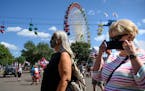 Fairgoers walked near the Great Big Wheel as the daily parade at the Minnesota State Fair took place behind them Tuesday afternoon.