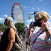 Fairgoers walked near the Great Big Wheel as the daily parade at the Minnesota State Fair took place behind them Tuesday afternoon.