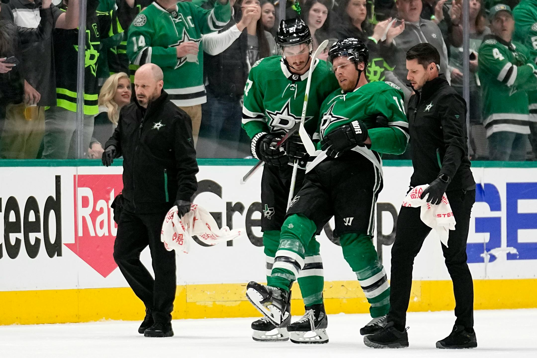 Dallas Stars' Joe Pavelski, second from right, is helped off the ice by Mason Marchment and staff after suffering an unknown injury in the second period of Game 1.