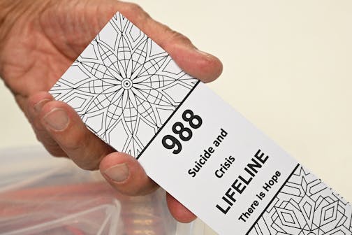 In this file photo, a bookmark for children with the 988 suicide and crisis lifeline emergency telephone number is displayed by Lance Neiberger, a volunteer with the Natrona County Suicide Prevention Task Force, while they speak about mental health and suicide awareness in Casper, Wyoming on Aug. 14, 2022. (Patrick T. Fallon/AFP via Getty Images/TNS) ORG XMIT: 86104689W