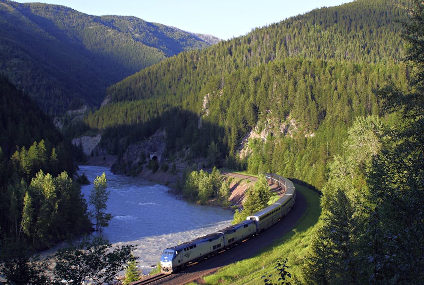 FILE - In this June 26, 2011 file photo, Amtrak's Empire Builder makes its way along the southern boundary of Glacier National Park near West Glacier, Mont. The park, accessible by Amtrak's Empire Builder passenger train, is home to seemingly endless mountain peaks, waterfalls, valleys, wildflowers and lakes. (Justin Franz/Flathead Beacon via AP)