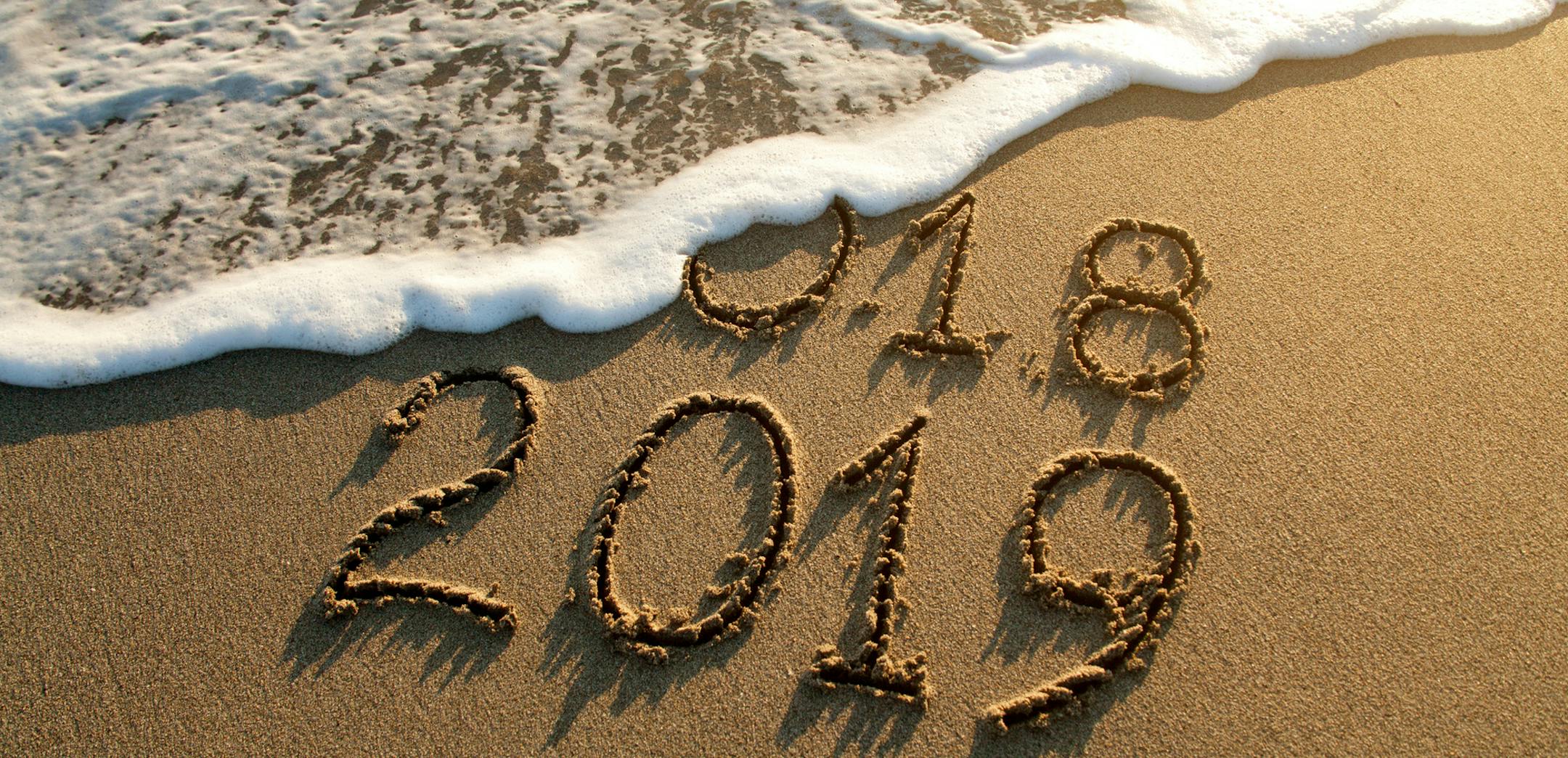 iStock
New year 2019 and old year 2018 written on sandy beach with waves.