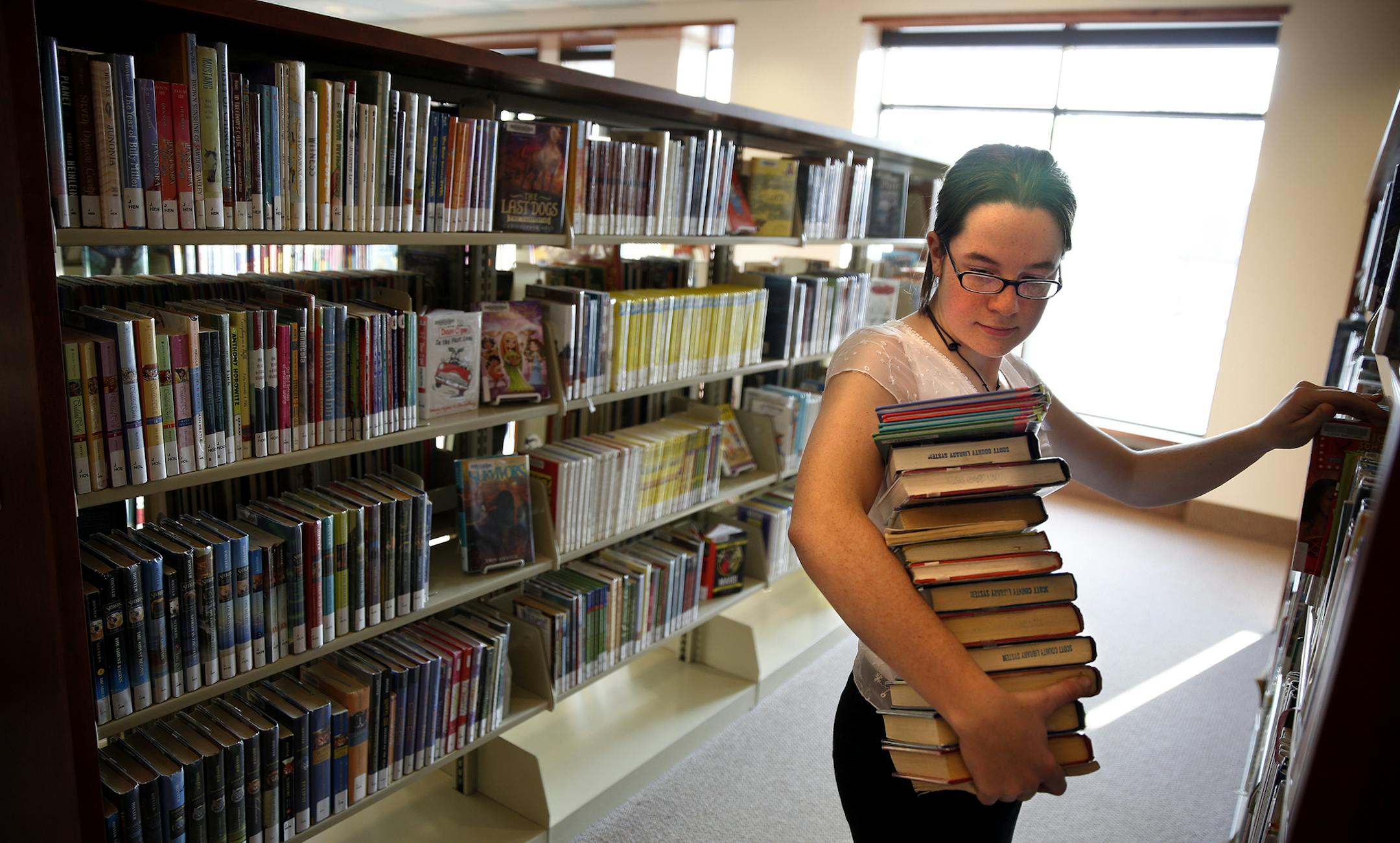 Library aide Sam Corcoran shelves books at the Prior Lake Library on Monday, December 8, 2014. ] LEILA NAVIDI leila.navidi@startribune.com /