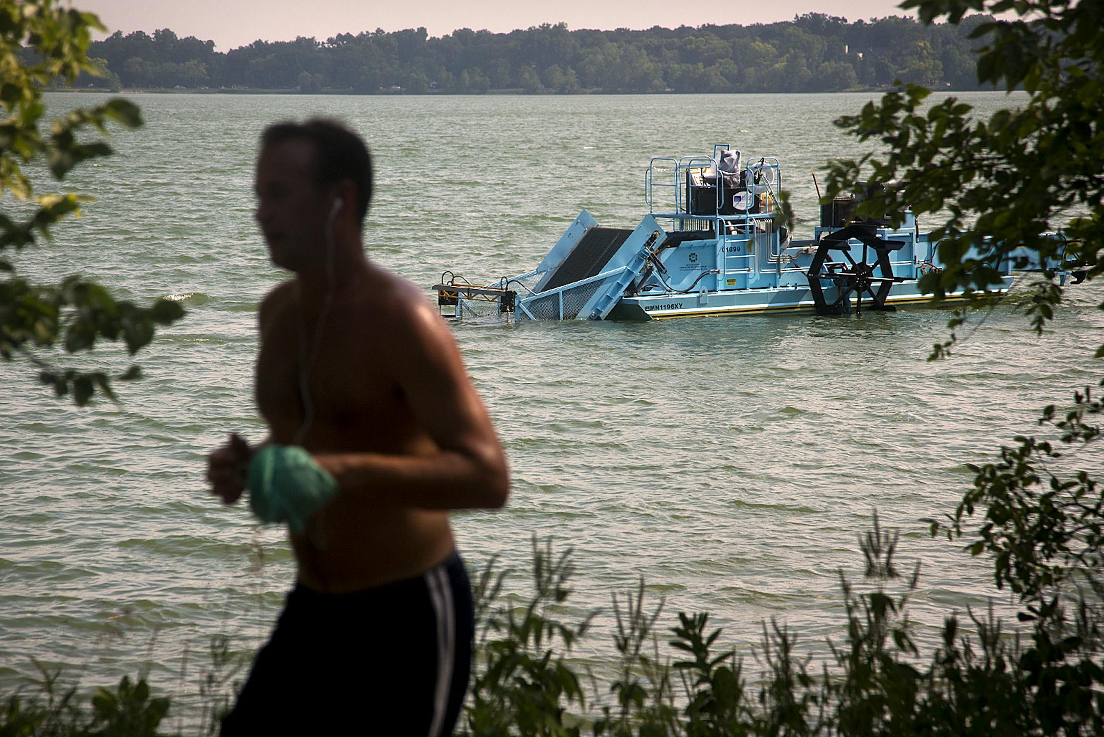 A runner ran past the milfoil mower near the shore of Lake Calhoun. The mower hasn&#x2019;t been used as much this year because there has been less milfoil to deal with.