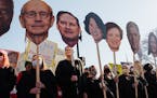 People hold signs featuring the faces of Supreme Court justices during a rally in front of the court building in Washington on Dec. 1, as the court he