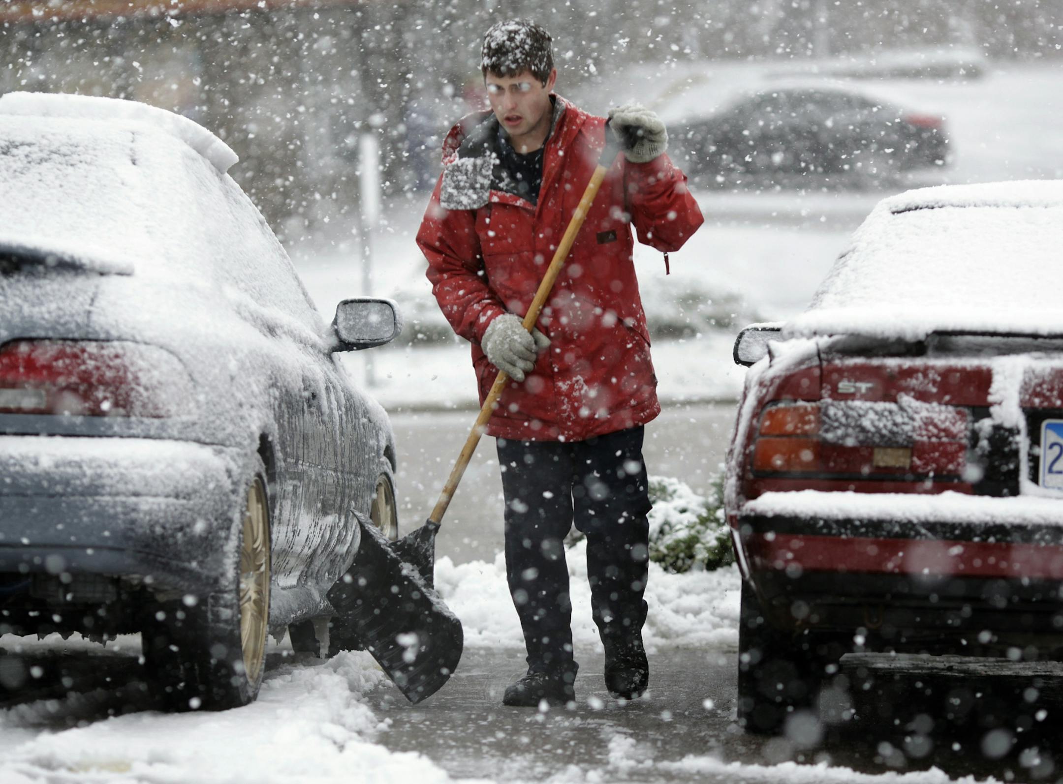 Tanner Hoffman shovels snow in a parking lot during a snowstorm Friday, Oct. 4, 2013, in Rapid City, S.D. Blizzards rolled into parts of Wyoming and South Dakota on Friday, bringing the states to an unseasonably early wintery standstill by closing highways and schools.