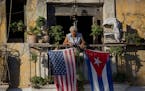 FILE - In this Dec. 19, 2014 file photo, Javier Yanez stands on his balcony decorated with U.S. and Cuban flags in Old Havana, Cuba. Roughly 45,000 Cu