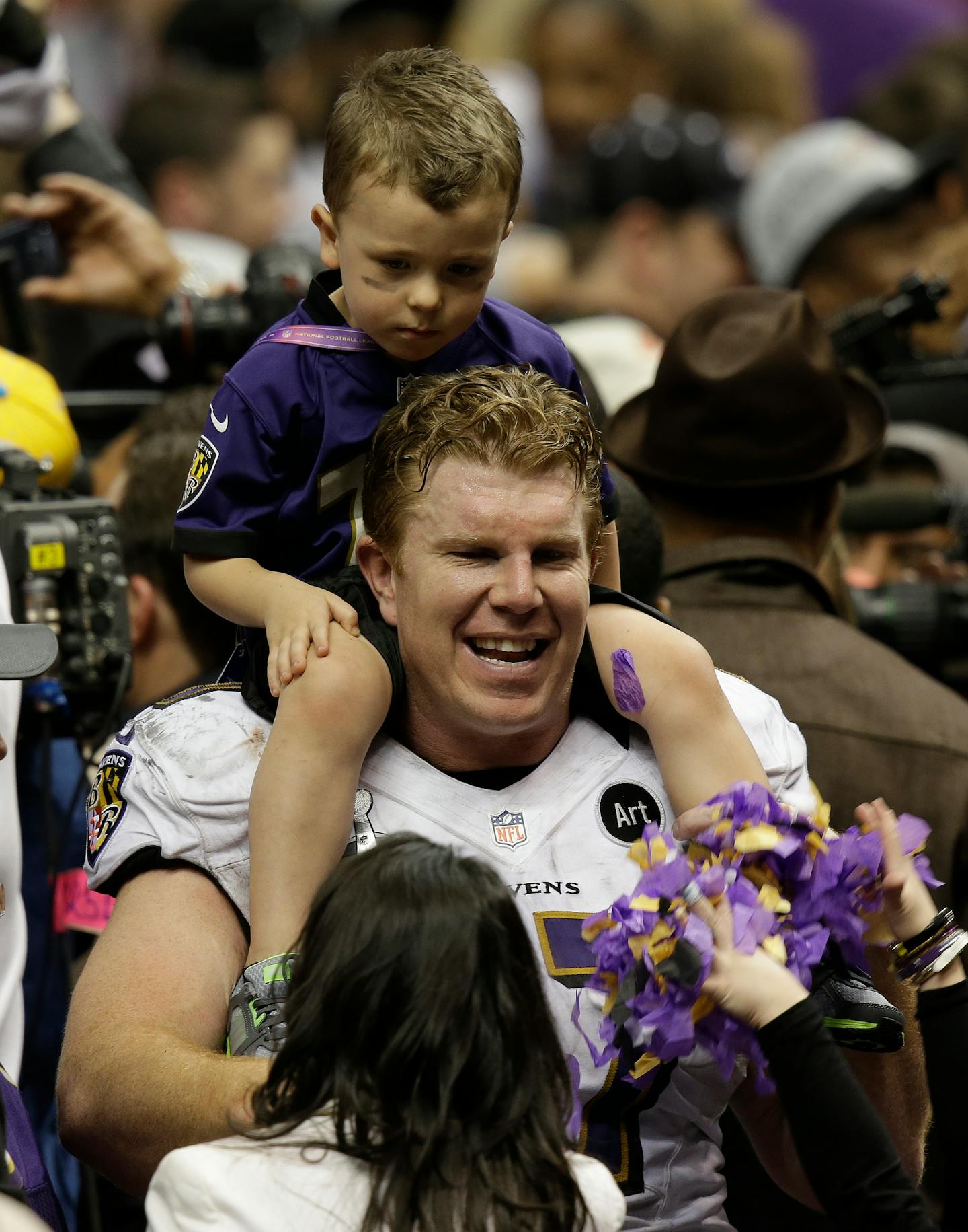 Baltimore Ravens center Matt Birk (77) holds a child after the NFL Super Bowl XLVII football game against the San Francisco 49ers Sunday, Feb. 3, 2013, in New Orleans. The Baltimore Ravens won 34-31. (AP Photo/Gene Puskar)