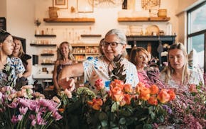 People enjoying flower arranging at a Sip 'n Bloom event.