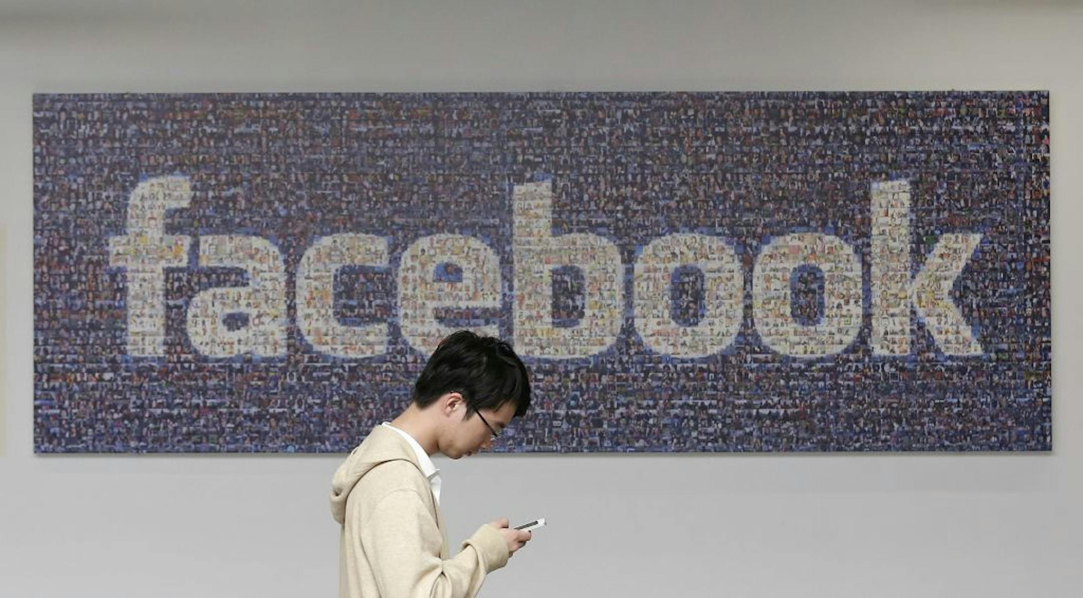 In this June 11, 2014 photo, a man walks past a Facebook sign in an office on the Facebook campus in Menlo Park, Calif. Facebook can't block nearly 400 search warrants seeking users' postings for a criminal fraud investigation, an appeals court said Tuesday