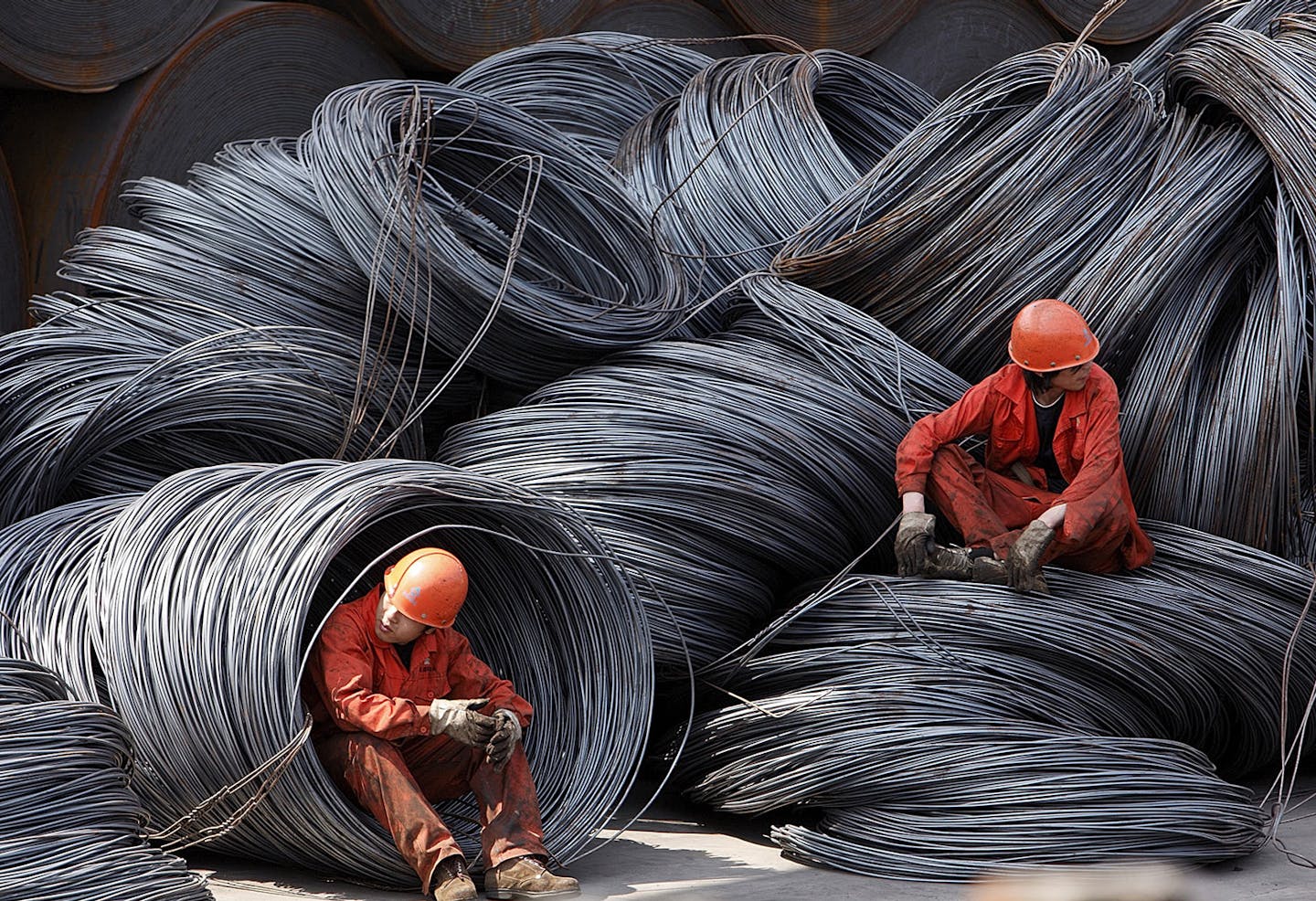 Workers take a break while sitting on a pile of steel wires at a stockyard run by the Shanghai Yirong Trading Co. Ltd in Shanghai, China, on Friday, April 10, 2009. China, the world's biggest iron ore buyer, boosted imports to a record in March for a second straight month, as smaller steelmakers turned to cheaper overseas suppliers. Photographer: Qilai Shen/Bloomberg News