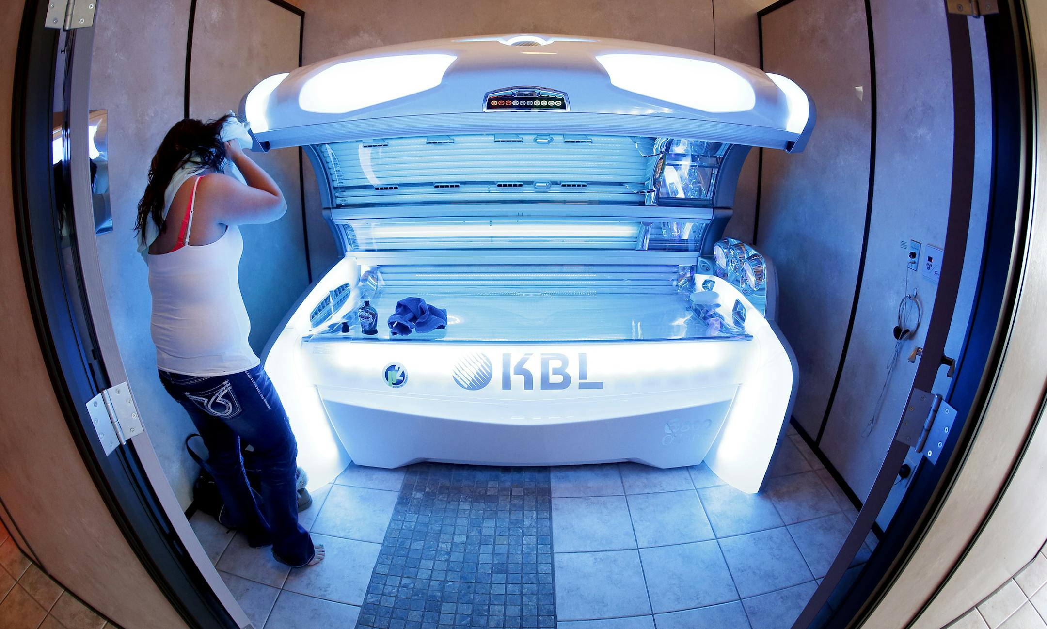 Ashley Blanshan, 22, of Blaine prepared to tan at Totally Tan in Golden Valley on Wednesday. Blanshan said she tans twice a week during the winter. ] CARLOS GONZALEZ cgonzalez@startribune.com - March 26, 2014 , Golden Valley, Minn., Totally Tan, A bill authored by Sen. Chris Eaton (DFL-Brooklyn Center) that would establish an age limit on the use of tanning equipment was recently sent to the Senate floor. S.F. 1901 would prohibit minors from using indoor tanning facilities and would require prop